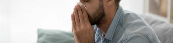 A man blowing his nose due to sinusitis