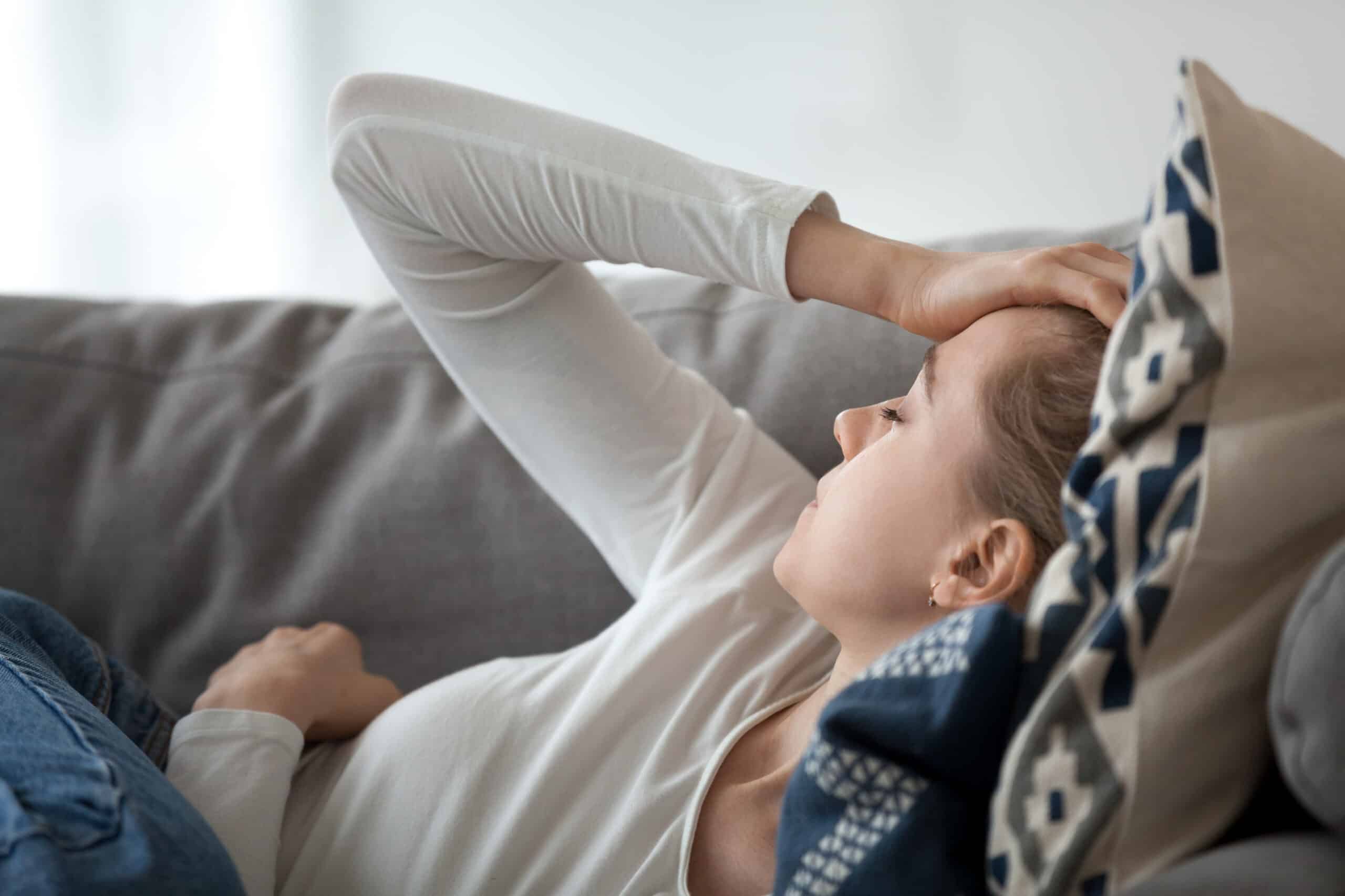 Person laying down grabbing their head.